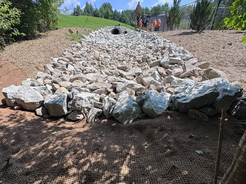Newly installed rip-rap dissipator at a culvert outlet with the Delcid crew at work