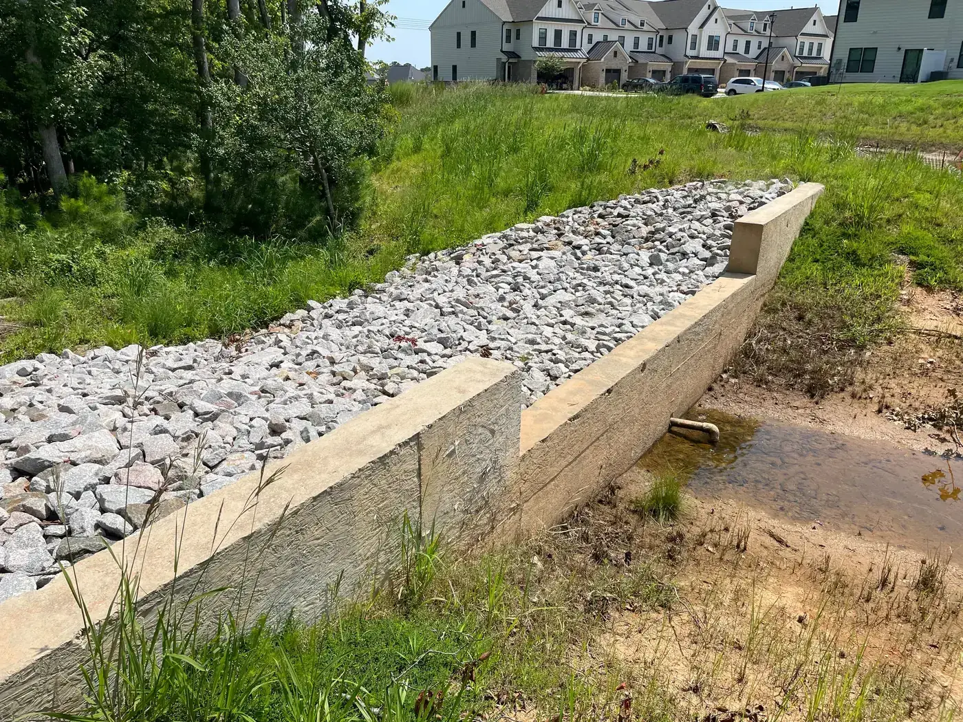 Completed concrete weir with stone rip-rap spillway