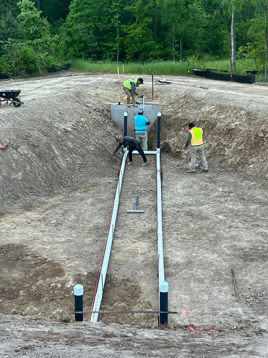 Team installing outlet pipe during basin grading